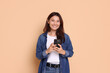 © New Africa - Smiling woman with smartphone on beige background