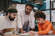 © BullRun - Focused group of workers studying together on project at table