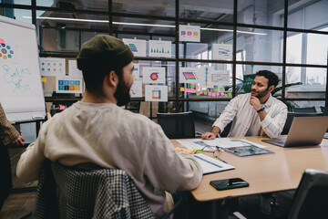 Wall Mural - Multiethnic colleagues sitting at table while working on project in office