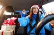 © Home-stock - Overjoyed young woman in Santa Hat driving car with Xmas gift boxes nearby and enjoy music, singing song feeling enjoyment of winter holiday preparation