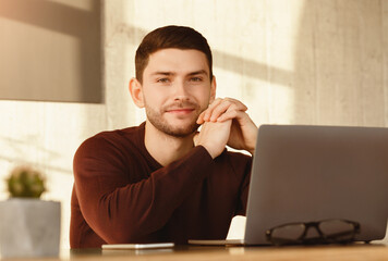 Poster - Successful Freelancer. Young Man At Laptop Smiling To Camera Sitting At Work Desk In Modern Office. Selective Focus