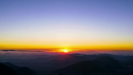 Poster - Sun rising above a sea of clouds creating a surreal gradient. The sky shifts from deep blue to vibrant orange and yellow hues as the sun ascends
