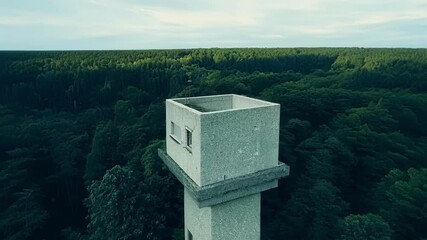 Poster - Lonely concrete observation tower rises above a vast green forest, offering a striking view of the surrounding wilderness
