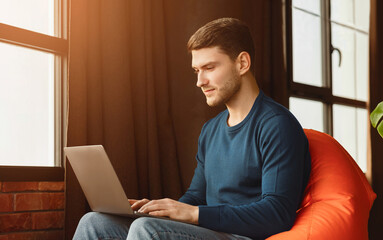 Poster - Computer Work. Freelancer Man Using Laptop Sitting In Beanbag Chair In Workspace Indoor.
