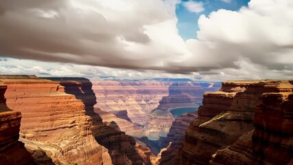 Poster - Light and shadow dance across the vast expanse of a canyon as clouds drift overhead, creating a captivating interplay of nature's elements