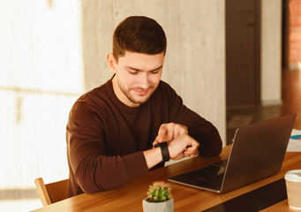 Poster - Working Hours. Office Worker Guy At Laptop Checking Time Sitting At Work Desk In Modern Office. Selective Focus