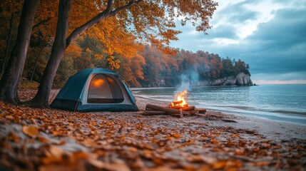 Poster - A cozy tent sits on the sandy shore of a lake, surrounded by colorful autumn leaves. A warm fire crackles nearby as evening approaches, creating a peaceful ambiance.