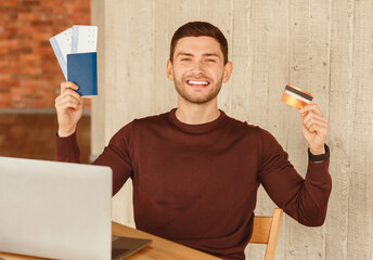 Poster - Ready For Vacation. Happy Guy Holding Flight Tickets And Credit Card Sitting At Work In Office. Selective Focus