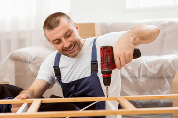 Aufkleber - Happy Craftsman Working Using Drill Tool Fixing Wooden Cabinet Sitting On Floor At Home. Professional Carpenter Repairing Furniture In Studio. Furnishing House Services, Carpentry Occupation.