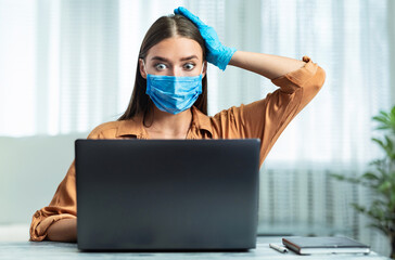 Disease Spreading. Scared young woman wearing protective mask and gloves reading news, grabbing head, front view