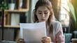 © ppearlgrey - woman appears stressed while holding documents in office setting. Her expression shows concern