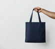 © easybanana - A hand is holding a blue tote bag. The bag is empty and has a simple design