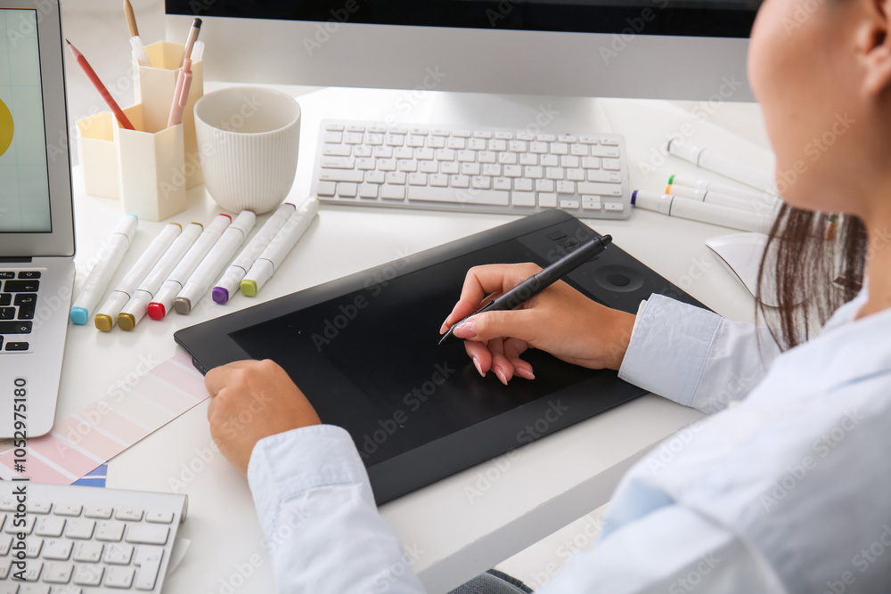 Female graphic designer working with tablet at table in office, closeup