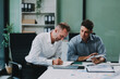 © ARMMY PICCA - Two businessmen working together Analyze financial reports with charts and graphs while using the calculator to calculate budget, income, taxes, business growth. Startup business idea.