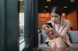 © Ton Photographer4289 - Young woman smiling and texting on smartphone while sitting in a coffee shop