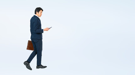 Leinwandbilder - スマホを見ながら歩く若い男性ビジネスパーソンの全身写真（切り抜き背景透過PNGも販売しております。作成者リンクから「PNG」で検索してください）