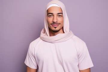 A man wearing a pink hoodie and scarf is smiling for the camera