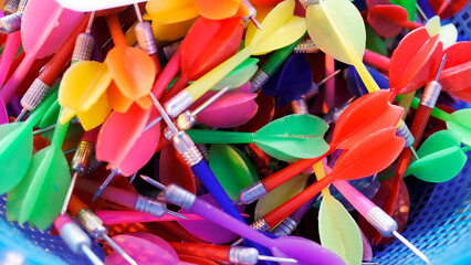 Top view of Colorful used darts in plastic basket contain ready for player in Carnival festival game pop balloons on the wall to win a prize at Thai Red Cross Fair night market fun fair