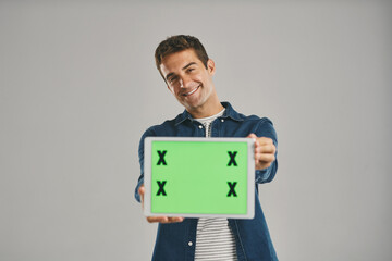 Poster - Portrait, green screen and man with tablet, internet and happy person on gray studio background. Face, guy and model with tech, tracking markers and promotion with digital app, showing and connection