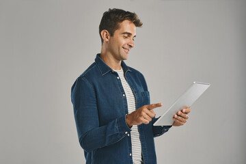 Poster - Search, smile and tablet with man in studio isolated on gray background for app download or update. Ecommerce, social media and website with happy user in casual outfit for online shopping or retail