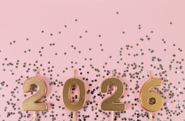 2026 Happy New Year. Top view of gold numbers, silver stars confetti on pink background. Copy space, flat lay.