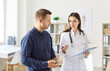 © Studio Romantic - Young man standing in office, listening carefully to female doctor. Physician or cardiologist with clipboard providing professional medical consultation, giving advices and describing treatment plan.
