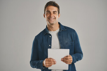 Poster - Confident, portrait and tablet with man in studio isolated on gray background for app download or update. Internet, social media and technology with happy user in casual outfit for online shopping