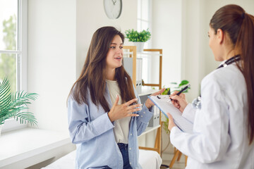 a young woman in a clinic talks to a doctor about her health, close-up. woman doctor listens to pati