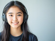 © Vasili - Young girl wearing headphones, smiling with joy as she listens to music. Her engaging expression reflects happiness and youthful energy.