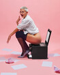 © master1305 - Humorous photography with young woman, office worker sitting on printer in unusual way against pink background, surrounded by papers. Flirty and quirky mood. Concept of business, corporate life