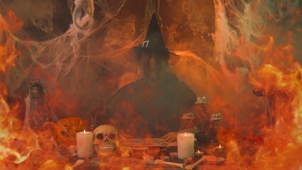 A witch in black clothing conjures up a skull sitting in a scary kitchen with pumpkins and potions.