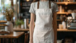 © Taras - Woman in empty apron. Waiter wearing black mockup wear for brand or label. Kitchen or restaurant worker with copyspace apron. Copy space in white uniform