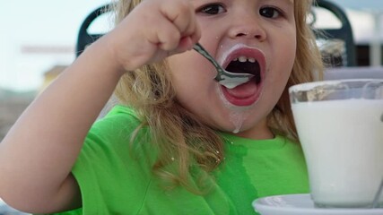 Wall Mural - Baby drink milk. Child have a meal. Hungry little kid eat milk with spoon. Baby porridge. Little baby eating healthy food. A Little baby eating her dinner. Close-up portrait of kid with cup of milk.