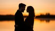 © Nitchalee N. - A romantic silhouette of a couple embracing during sunset by a serene body of water, capturing a moment of love and connection.