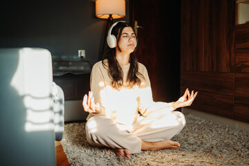 Young caucasian woman meditating with wireless headphones at home	
