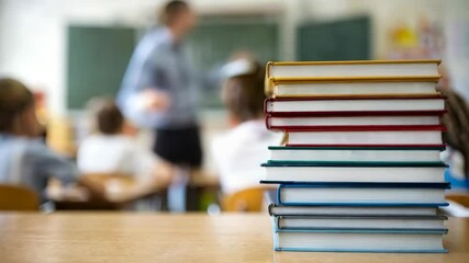 Poster - A classroom scene with stacked books in the foreground and a teacher addressing students.