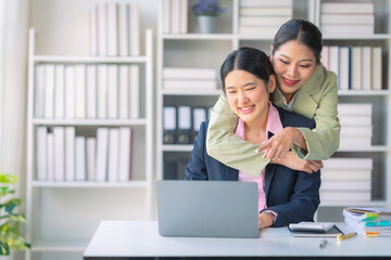 Two Asian businesswomen are deeply engaged in a discussion about data analysis work on a computer screen with graphs and charts. Showcase teamwork