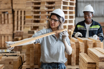 woman wearing safety uniform and hard hat working quality inspection of wooden products at workshop manufacturing wooden. female carpenter worker wood warehouse industry.