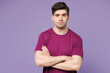 © ViDi Studio - Young sad frowning mad Caucasian man he wears violet t-shirt casual clothes hold hands crossed folded look camera isolated on plain pastel light purple background studio portrait. Lifestyle concept.