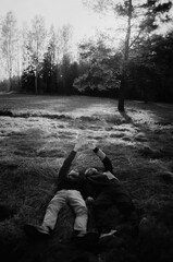 A black and white photograph of two men lying in a field on a sunny autumn day, gazing dreamily at the sky.