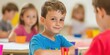 © Kamonwan - Smiling boy engaging in creative activity with classmates in a lively classroom.
