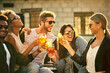 © peopleimages.com - Friends, city and cheers with drinks at party, social event and celebration of relationship. People, sunglasses and toast with alcohol for bonding in town, diversity and outdoor for love or support