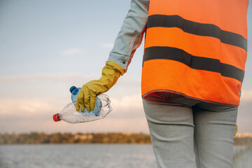 Trash pollution. Close up view of female volunteer that is holding plastic bottle.