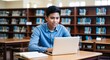 © Arceli - Filipino student studying on laptop motivated expression casual shirt library with shelves and tables late teens male