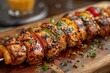 © nurionstudio - Grilled chicken and bell pepper skewers with fresh herbs on a wooden board.
