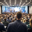 © DesignRevel - Blurry Rear View of Audience in Conference Hall Watching Speaker at Business Event.
