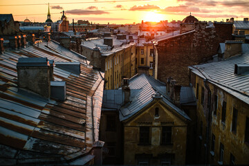 A view of Saint Petersburg rooftops at sunset, bathed in warm, golden light, capturing the romantic charm of the city's skyline.