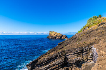 Wall Mural - A view past rock outcrops towards the Dog Face islet on the island of San Miguel in the Azores in summertime
