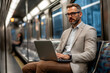 © Di Studio - portrait of  businessman in suit with laptop in a subway train
