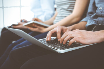 Wall Mural - Group of casual dressed business people working at meeting or conference, close-up of hands. Businessman using laptop computer. Teamwork or coaching concept